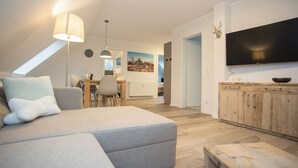 Un salon moderne avec un canapé, une table à manger et un téléviseur.