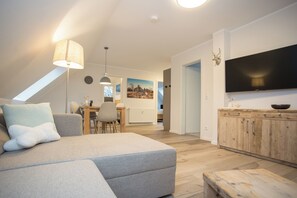 A modern living room with a sofa, dining table, and TV.