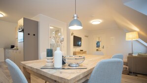 Une cuisine moderne avec une table à manger en bois, des chaises bleu clair et un luminaire suspendu.