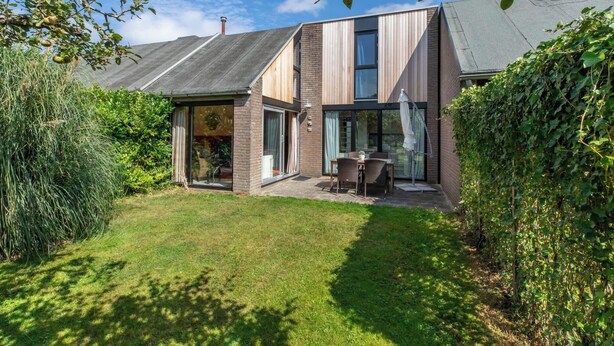 Ein modernes Haus mit Satteldach, großen Fenstern und einem gepflegten Rasen.