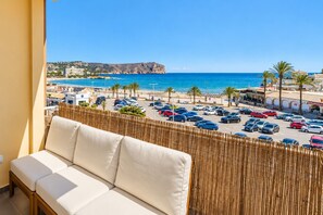 Een balkon met uitzicht op een strand, auto's en gebouwen.