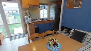 A compact kitchen with a dining area, a sofa, and a view of the outdoors. - Mobile homes in the countryside  (Saint-Loup)