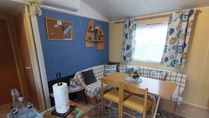 A compact living space with a kitchenette, a dining area, and a seating area with a sofa and table. - Mobile homes in the countryside  (Saint-Loup)