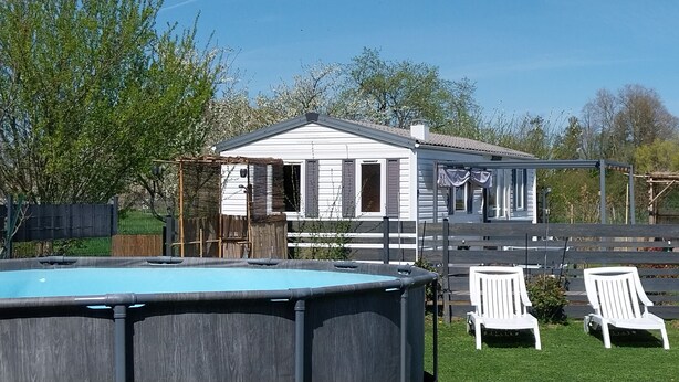 A pool area with two white chairs and a small table with gnome decorations. - Mobile homes in the countryside  (Saint-Loup)