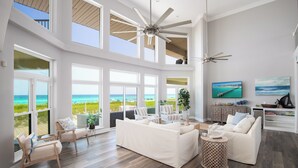 A spacious living room with a large white sofa, two armchairs, and a coffee table. There are multiple windows offering views of the ocean. - Beachfront Luxury Estate Sleeps 20 & Allows Events (Navarre)