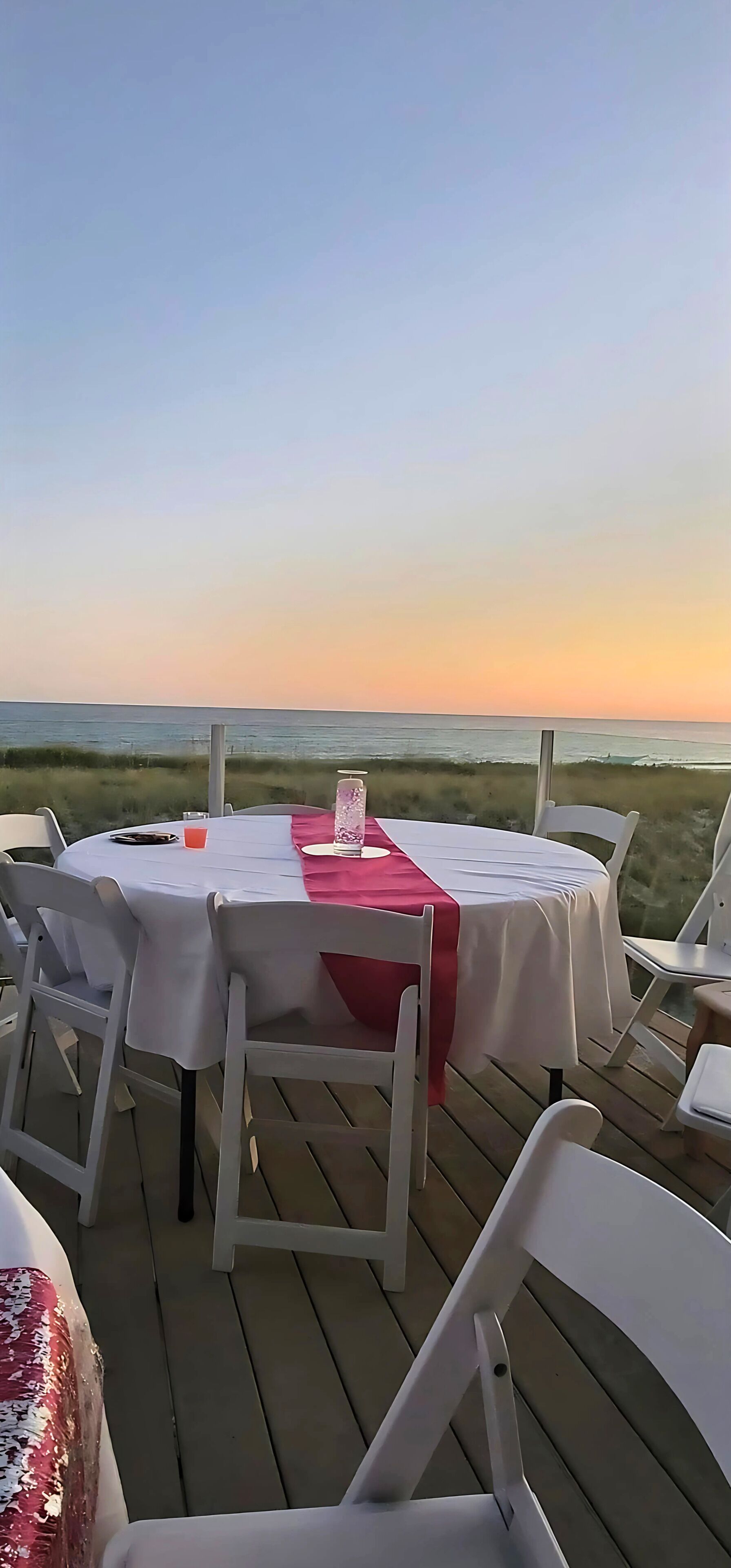 An outdoor dining area with a table set for two, overlooking a body of water.