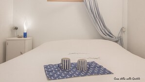 A bedroom with a bed, a bedside table with a lamp, and a window with curtains.