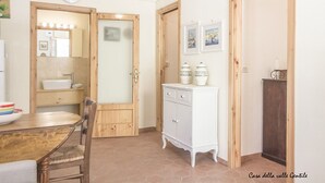 A room with a wooden door, a white cabinet, a mirror, and a clock on the wall.