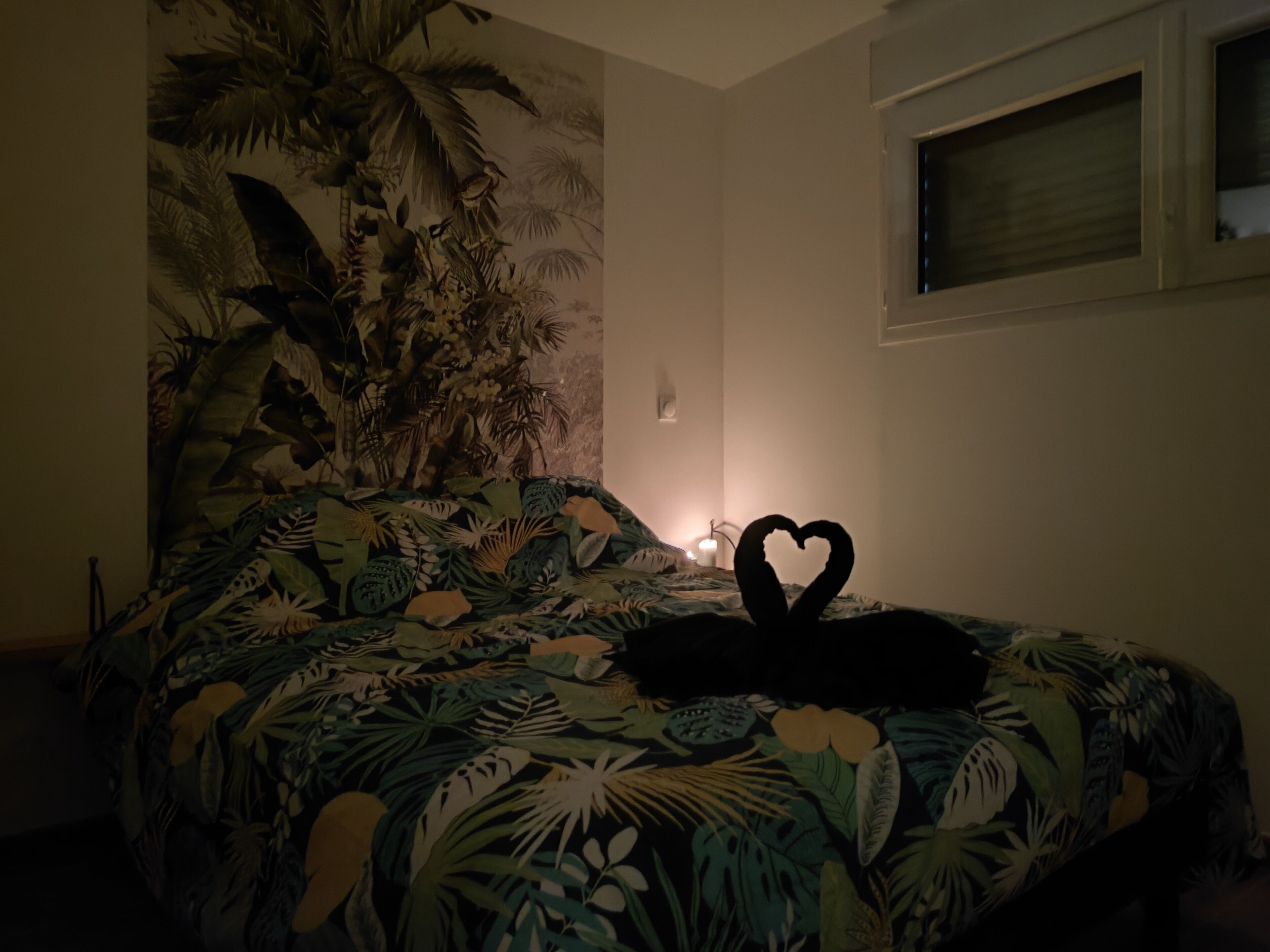 A bedroom with a bed featuring a tropical leaf pattern.