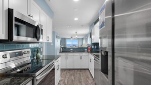 A modern kitchen with stainless steel appliances, white cabinets, and a view to the outside. - The Palms #501 (Fort Walton Beach)