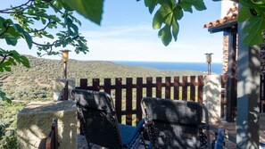 A terrace with two chairs, a stone wall, and a view of the sea. - Casa Cedro in Luddui (Budoni)