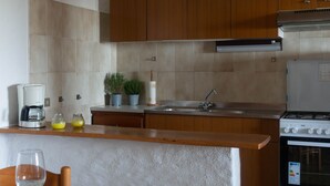 A kitchen with wooden cabinets, a stainless steel sink, and a stove. - Casa Cedro in Luddui (Budoni)
