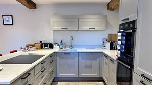 Une cuisine moderne avec des meubles gris, un réfrigérateur noir et un plancher en bois.