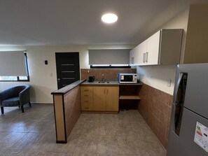 Kitchen area with central island, sink, microwave, and refrigerator, offering a view from the window.