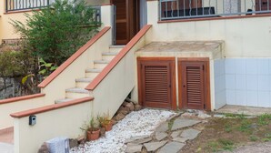 A two-story house with a stone staircase, wooden shutters, and a balcony with a metal railing. - La Casa di Salvatore (Budoni)