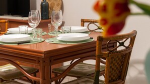 A dining table set with plates, glasses, and cutlery, surrounded by wicker chairs. - La Casa di Salvatore (Budoni)