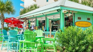 A beachside restaurant with outdoor seating, a Coca-Cola branded umbrella, and a sign for 'Fudpuckers'. - Waterscape 235-a (Fort Walton Beach)