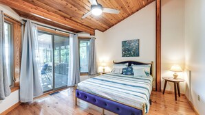 Ein Schlafzimmer mit Holzbalkendecke, einem Bett mit blau-weiß gestreifter Bettdecke, zwei Nachttischlampen und einem Bild an der Wand.