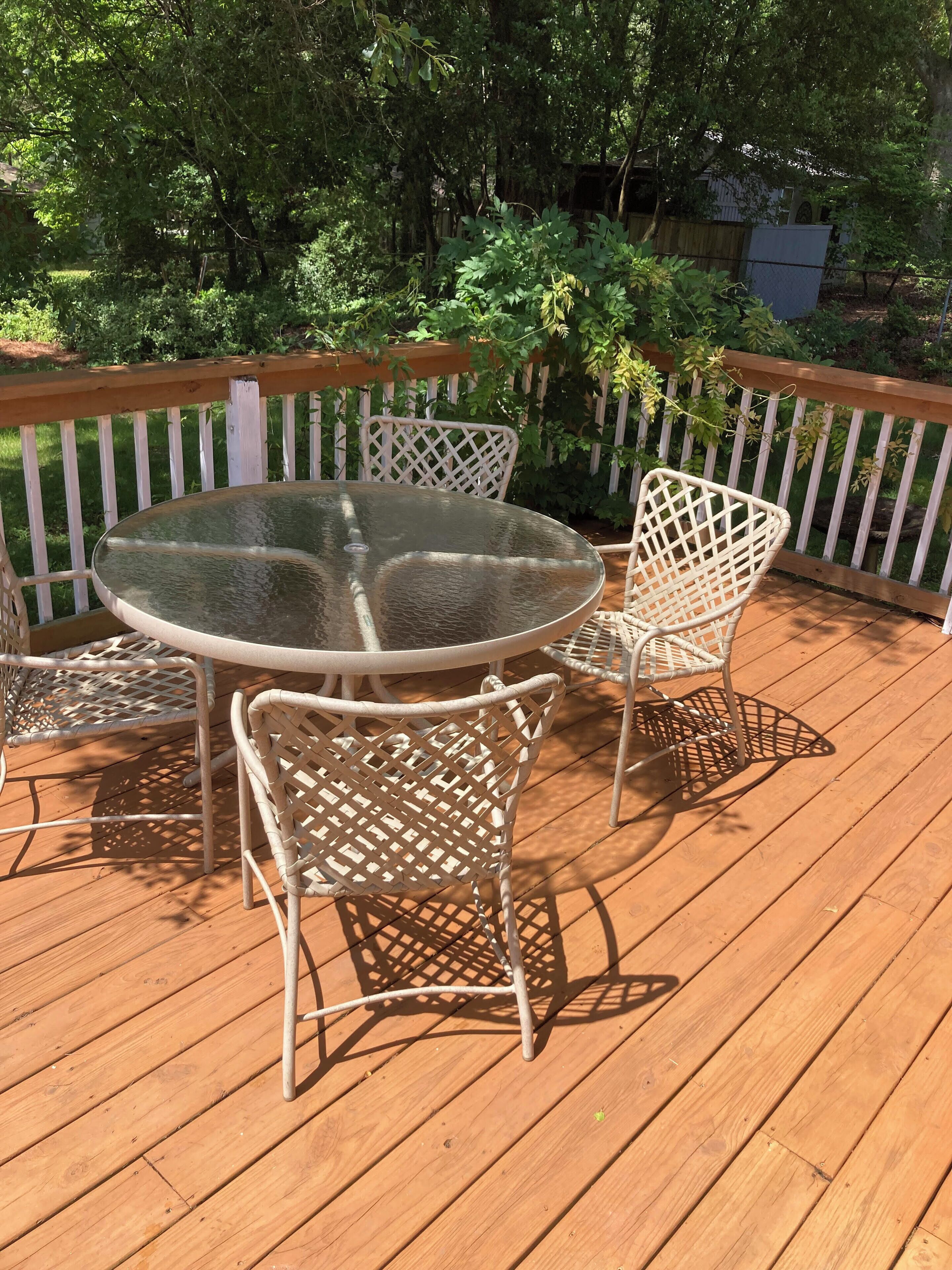 Une terrasse en bois avec une table ronde en verre et deux chaises en osier.