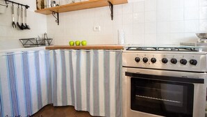 Een keuken met een strepen tafelkleed, een gasfornuis en een inbouwoven.