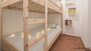 Een slaapkamer met een stapelbed, een klein plankje en een ingelijst foto op de muur.
