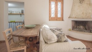 Een gezellige woonkamer met een houten eettafel, een bank en een open haard.