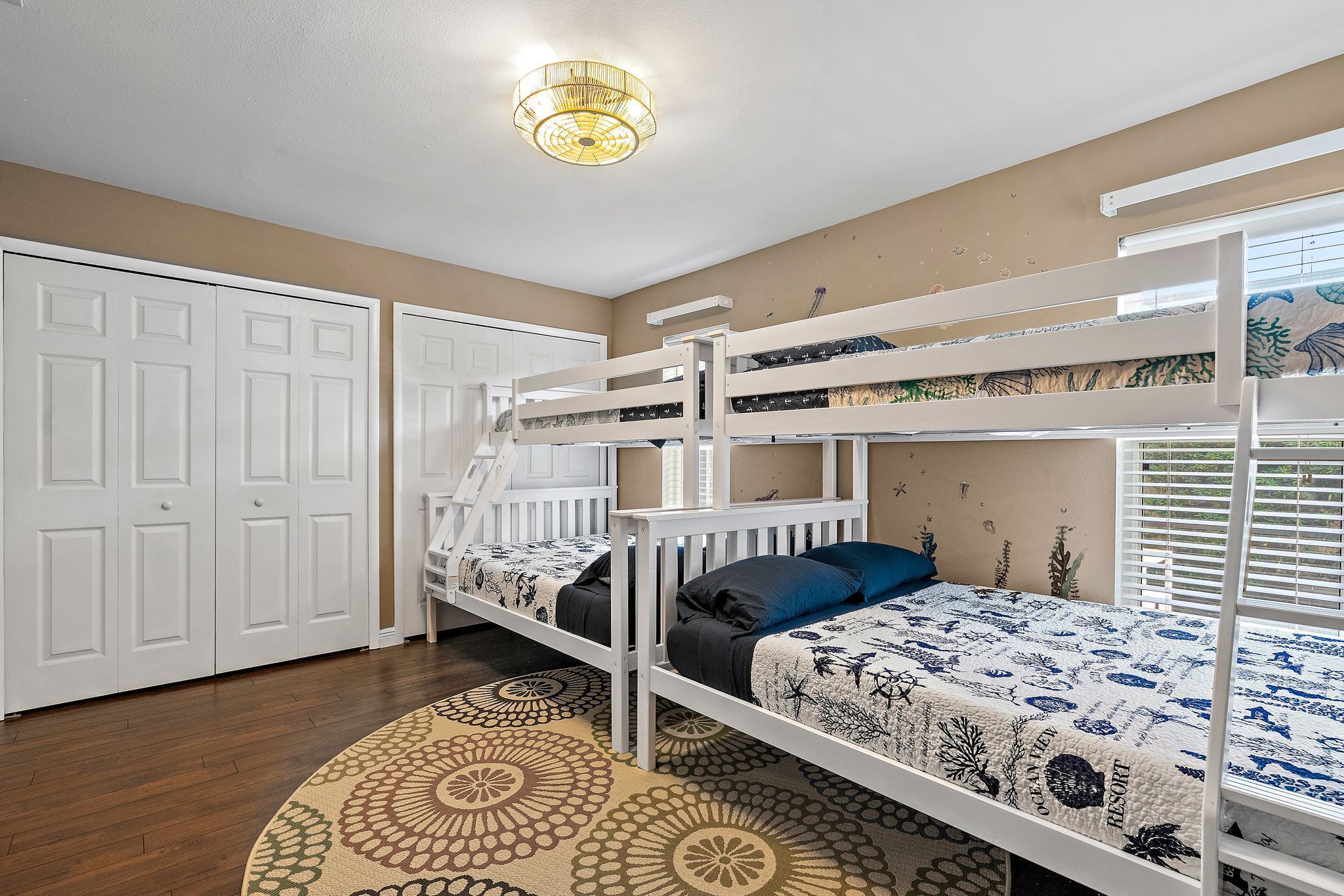 A bedroom with bunk beds, a patterned rug, and a ceiling light fixture.