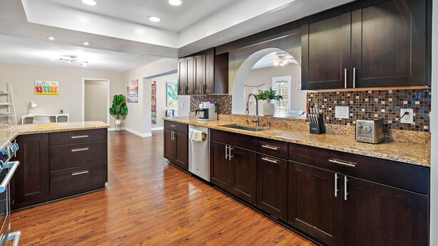 A modern kitchen with dark wood cabinets, granite countertops, and a central island.