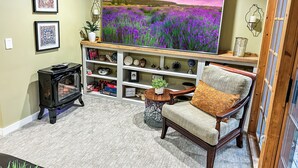 Una sala de estar con un televisor de pantalla plana grande, una chimenea, un sillón cómodo y una estantería con objetos decorativos.