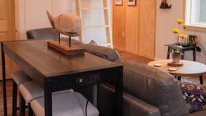 Un salon moderne avec une table à manger en bois, un canapé en cuir et un escalier menant à un niveau supérieur.
