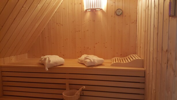 Un sauna en bois, avec des bancs, des serviettes et un seau en bois.