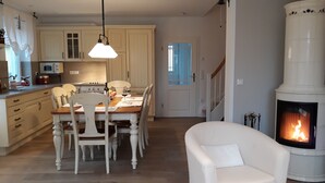 Une cuisine chaleureuse avec des meubles en bois, une table à manger pour quatre personnes et une cheminée blanche.
