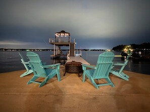 A waterfront deck with two Adirondack chairs and a small table, overlooking a body of water and a dock with a gazebo. - Deep water that does not dry. Perfect fishing off dock. (Mabank)