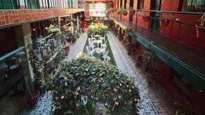 A courtyard with potted plants, outdoor seating, and a tiled floor. - Hotel Willcamayu  (Pisac)