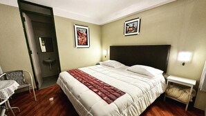 A hotel room with a large bed, a bedside table, a chair, and a small table. - Hotel Willcamayu  (Pisac)