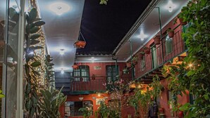 A courtyard with potted plants, a fire extinguisher, and a tiled walkway. - Hotel Willcamayu  (Pisac)