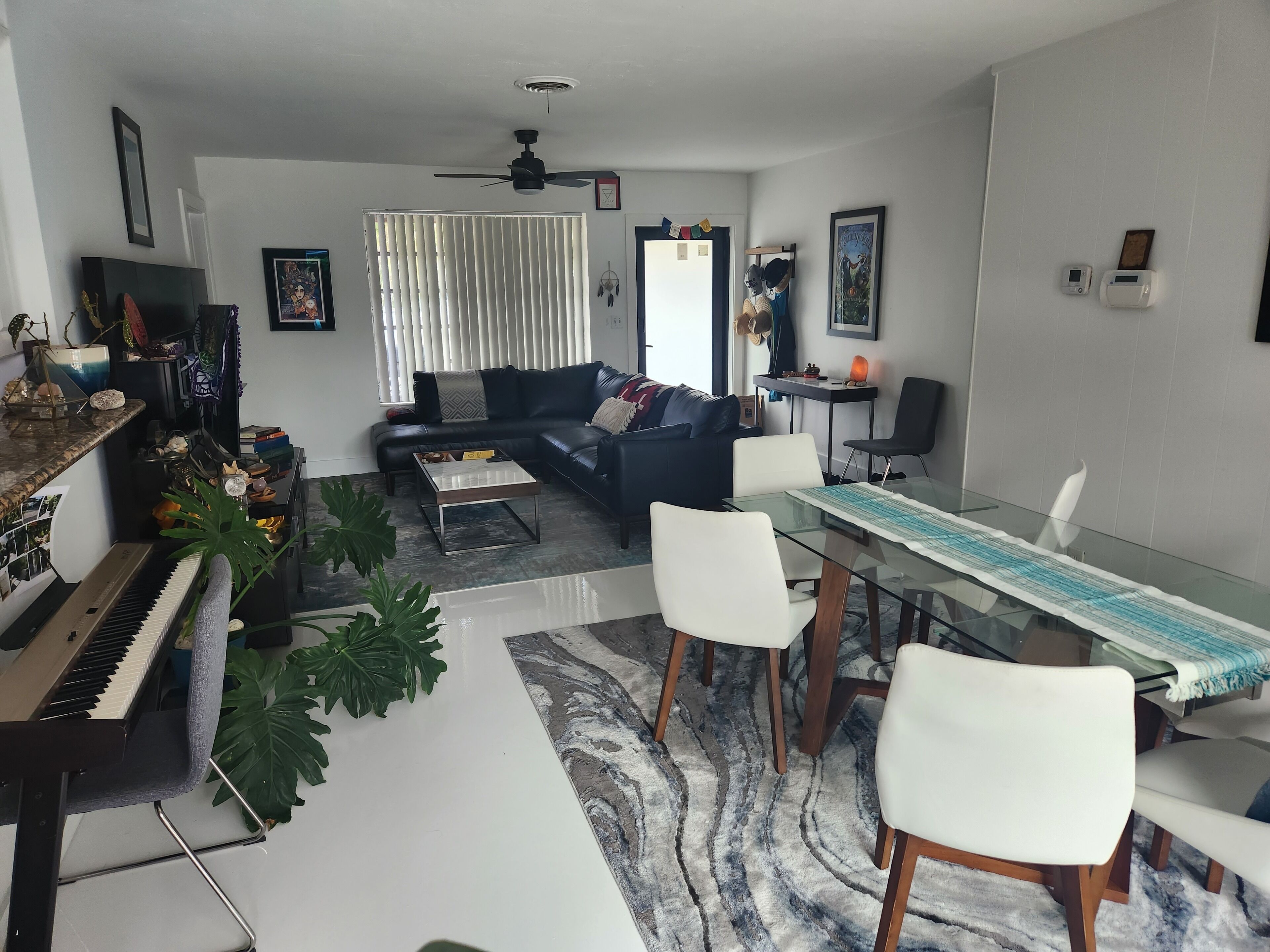 Ein Wohnzimmer mit Klavier, Sofa, Couchtisch und Esstisch mit Stühlen.
