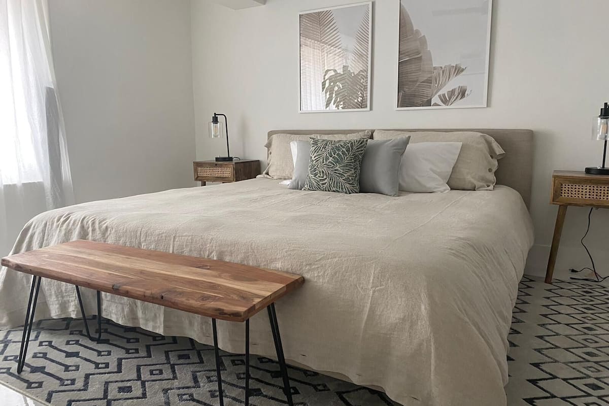 Une chambre à coucher avec un lit, des tables de chevet, un banc et des tapis à motifs.