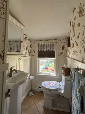 A bathroom with a sink, toilet, and window.