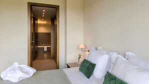 A hotel room with a bed, a nightstand with a lamp, and a bathroom visible through an open door.
