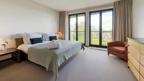 A hotel room with a large bed, a desk, a chair, and a dresser.