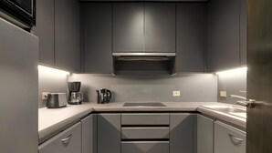A modern kitchen with grey cabinets, a built-in microwave, a coffee maker, and a sink.