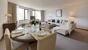 A hotel room with a dining area, a sofa, and a TV.