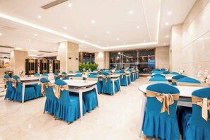 Une salle de banquet avec des tables rondes, des chaises et des nappes bleues.