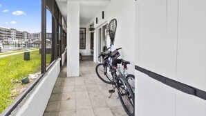 A corridor with tiled flooring, a bike rack, and a view of buildings through large windows.