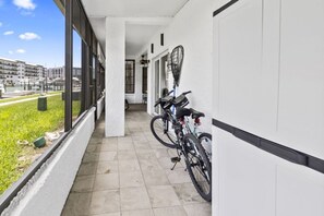 A corridor with tiled flooring, a bike rack, and a view of buildings through large windows.
