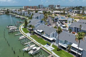 A marina with boats docked, modern buildings with large windows, and a clear view of the ocean.