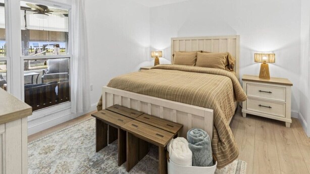 A bedroom with a bed, bedside tables, a bench, a window, and a view of the outside.