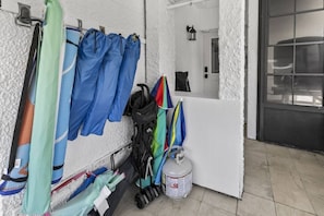 Um quarto com parede branca texturizada, uma janela e uma porta. Vários guarda-chuvas azuis e verdes pendem na parede.