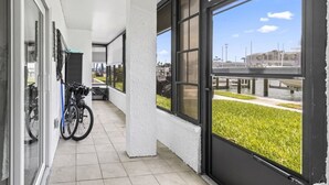 A covered outdoor area with a bicycle rack, a glass door, and a view of a marina.